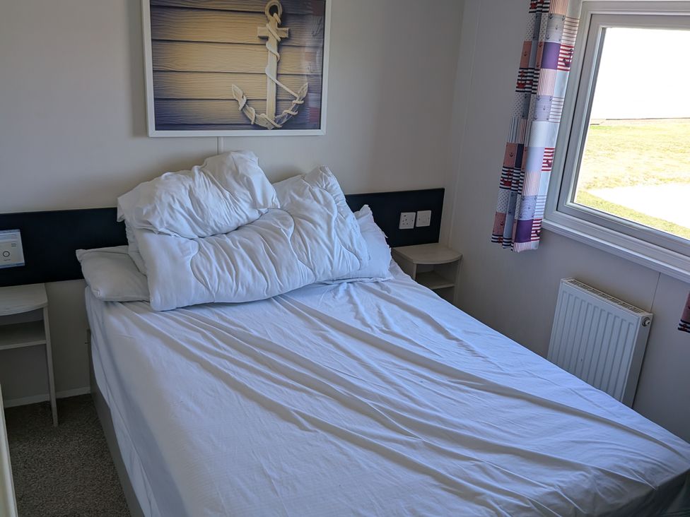 A bedroom with a bed and window at Presthaven - Denbigh Dunes Prestatyn