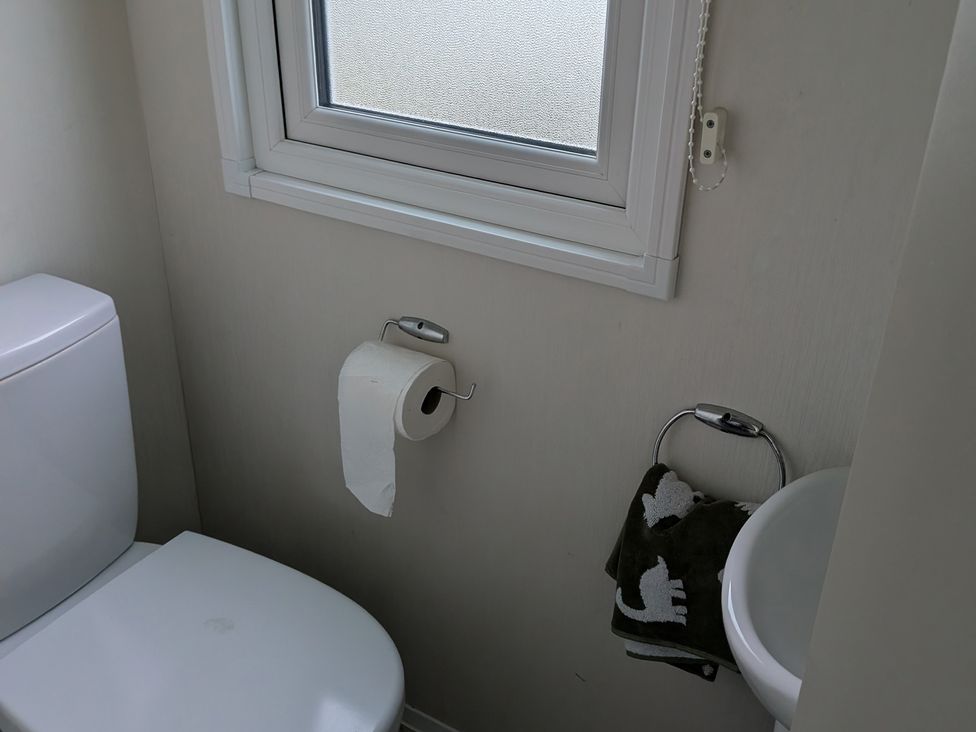 A bathroom with a toilet and window at Presthaven - Denbigh Dunes in Gronant