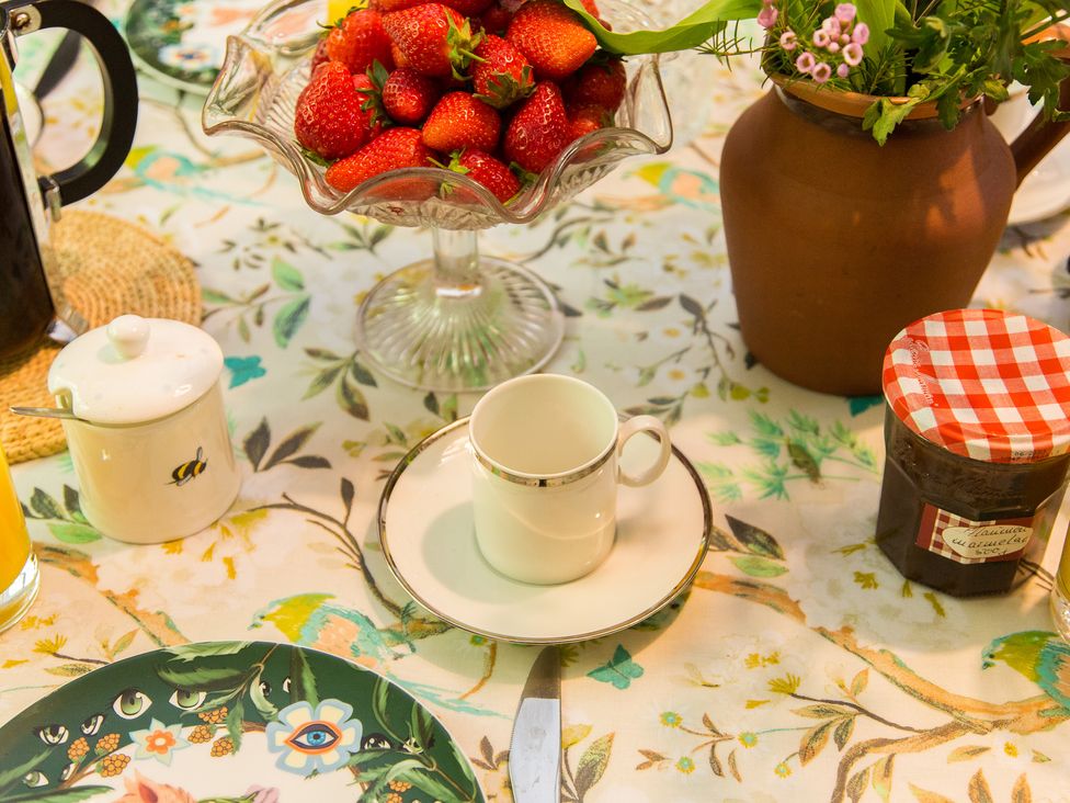 A dining table set with strawberries and a teacup at Whitebeams Pett Bottom near Stelling Minnis