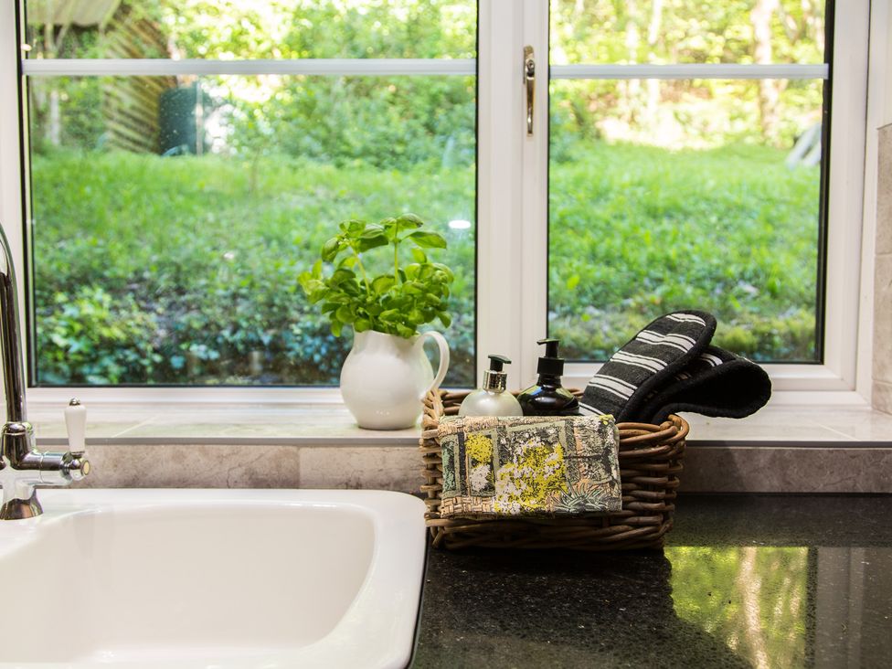 A sink with a basket of toiletries and a plant at Whitebeams in Pett Bottom near Stelling Minnis