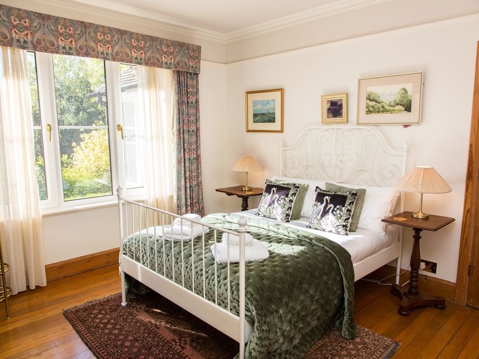 A bedroom with a bed, pillows, lamps, and paintings at Whitebeams Pett Bottom near Stelling Minnis