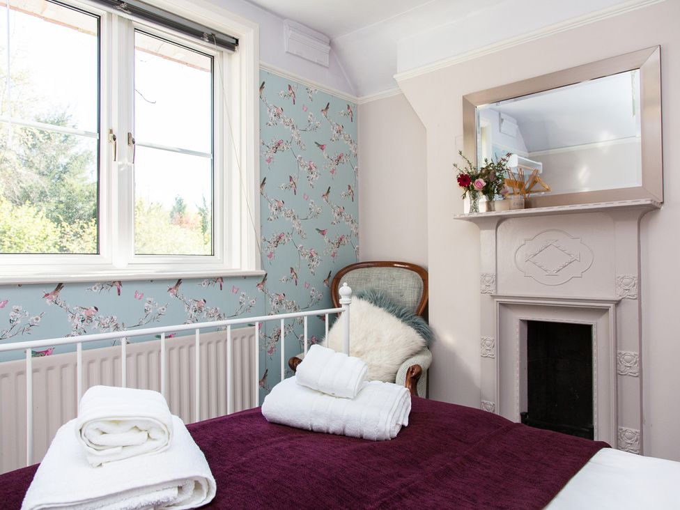 A bedroom with a bed, chair, and window at Whitebeams in Pett Bottom near Stelling Minnis