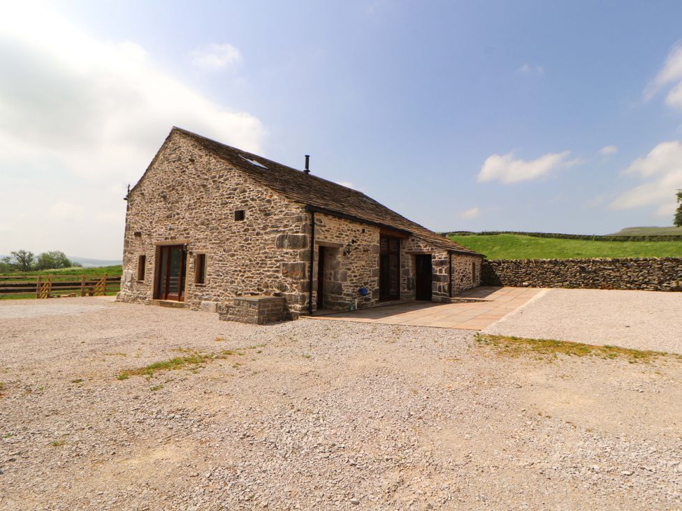A stone building with a parking area and patio at Dam House Barn in Lancaster