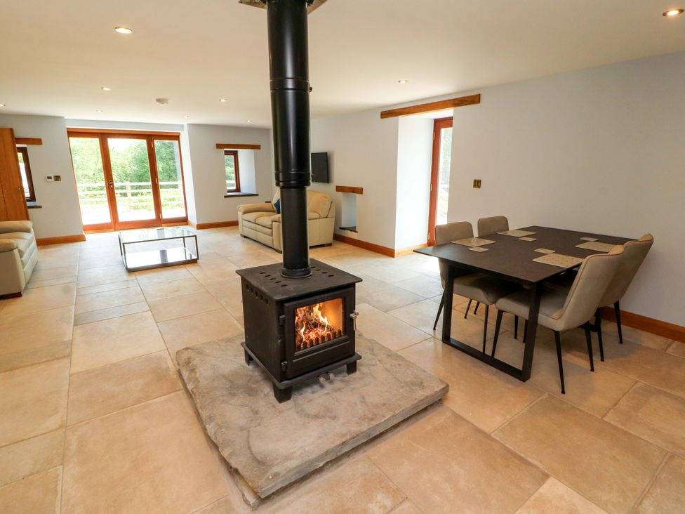 A living room with a stove and dining table at Dam House Barn in Lancaster