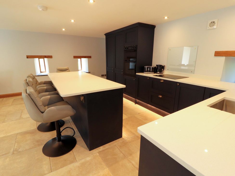 A kitchen with a kitchen island and bar stools at Dam House Barn Lancaster