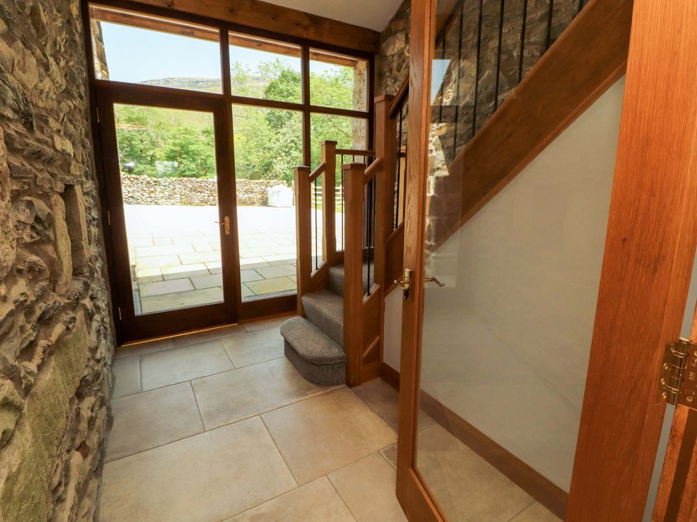 An entrance hall with stairs and glass doors at Dam House Barn in Lancaster