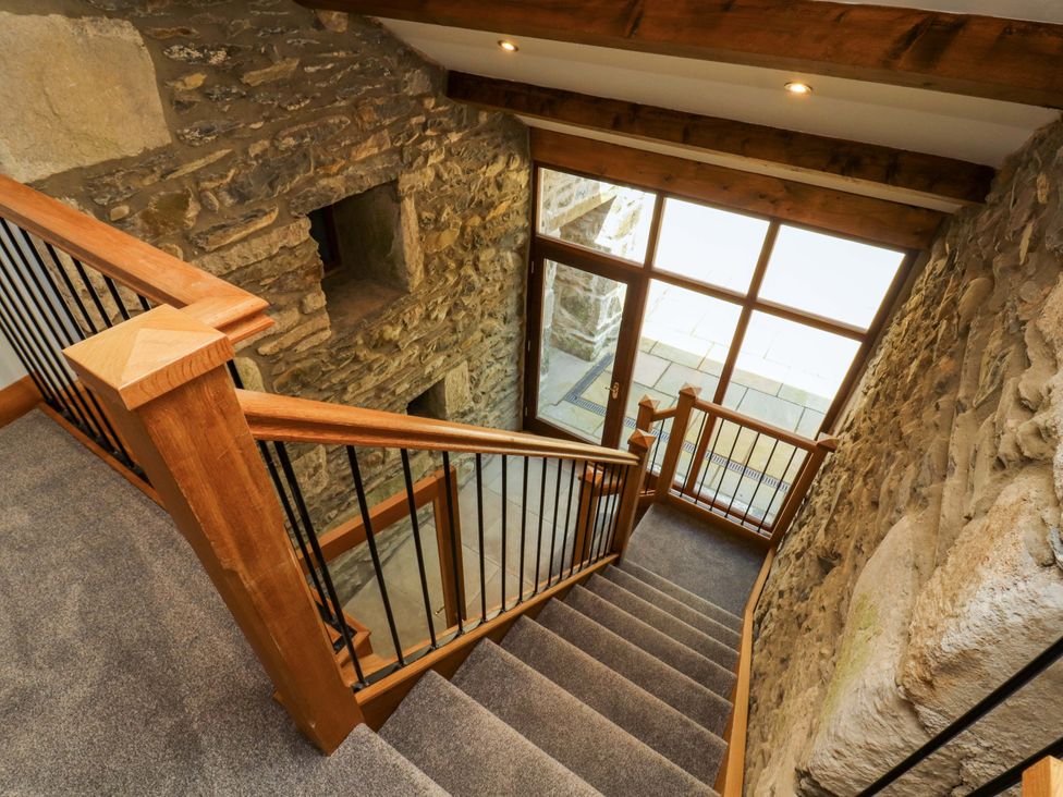A staircase with wooden railing and stone wall at Dam House Barn in Lancaster