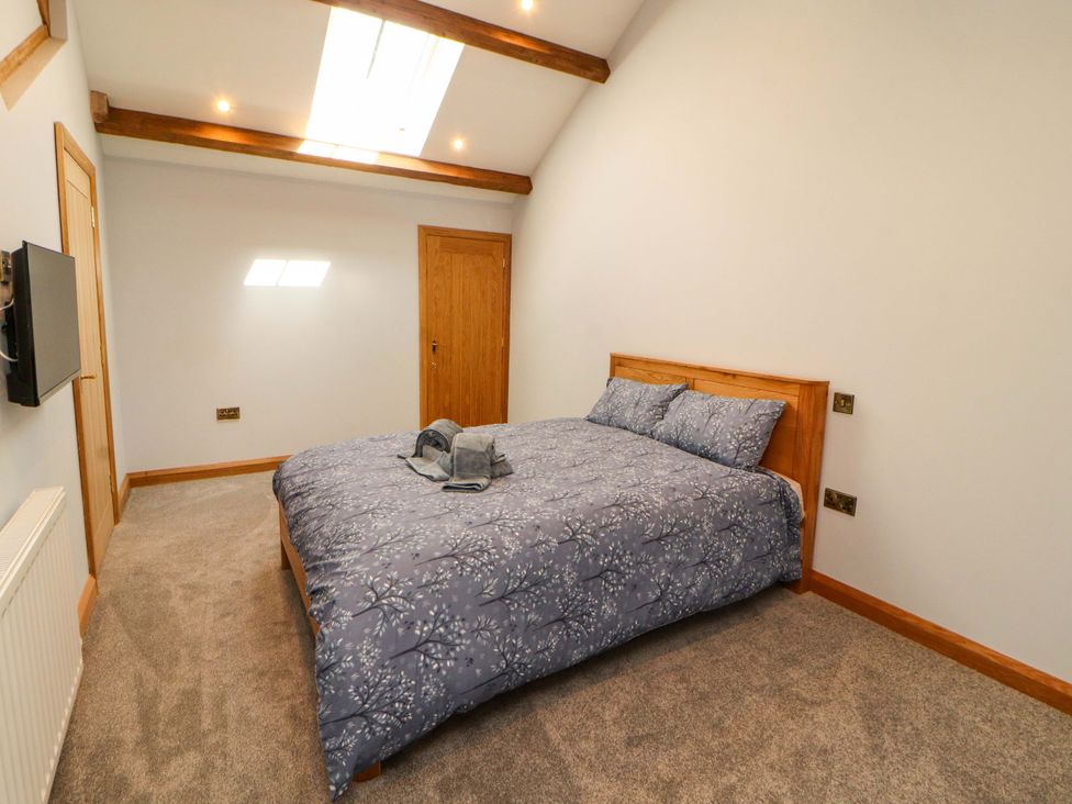 A bedroom with a bed and television at Dam House Barn in Lancaster