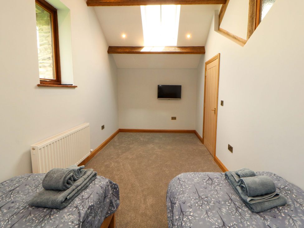 A bedroom with two single beds and a tv at Dam House Barn in Lancaster