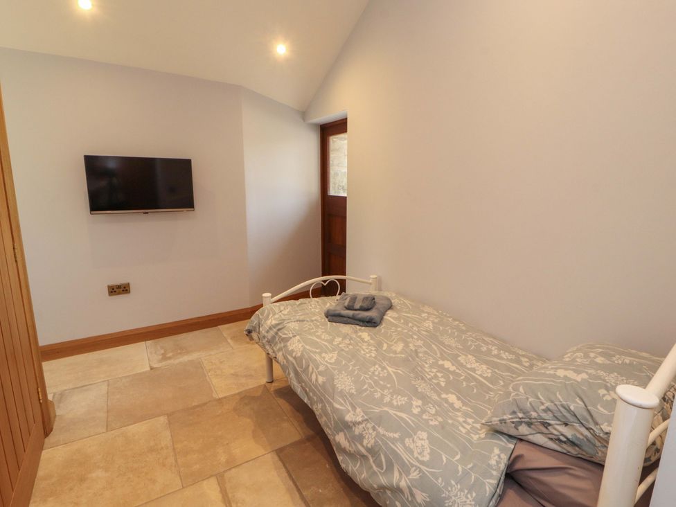 A bedroom with a bed and television at Dam House Barn in Lancaster