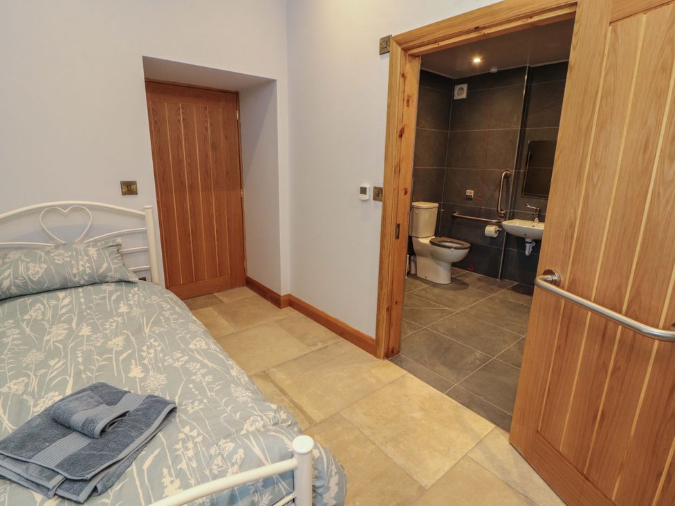 A bedroom with a bed and bathroom access at Dam House Barn in Lancaster