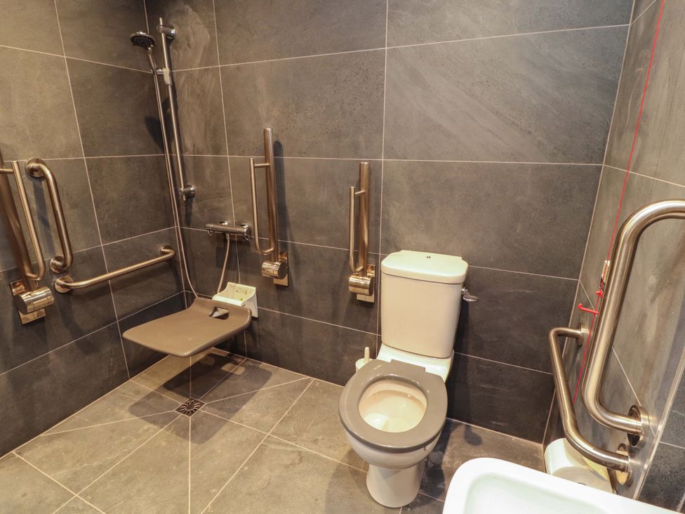 A bathroom with shower, toilet, and grab bars at Dam House Barn in Lancaster