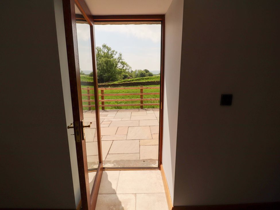 A doorway leading to a patio area with a view of grass fields at Dam House Barn in Lancaster