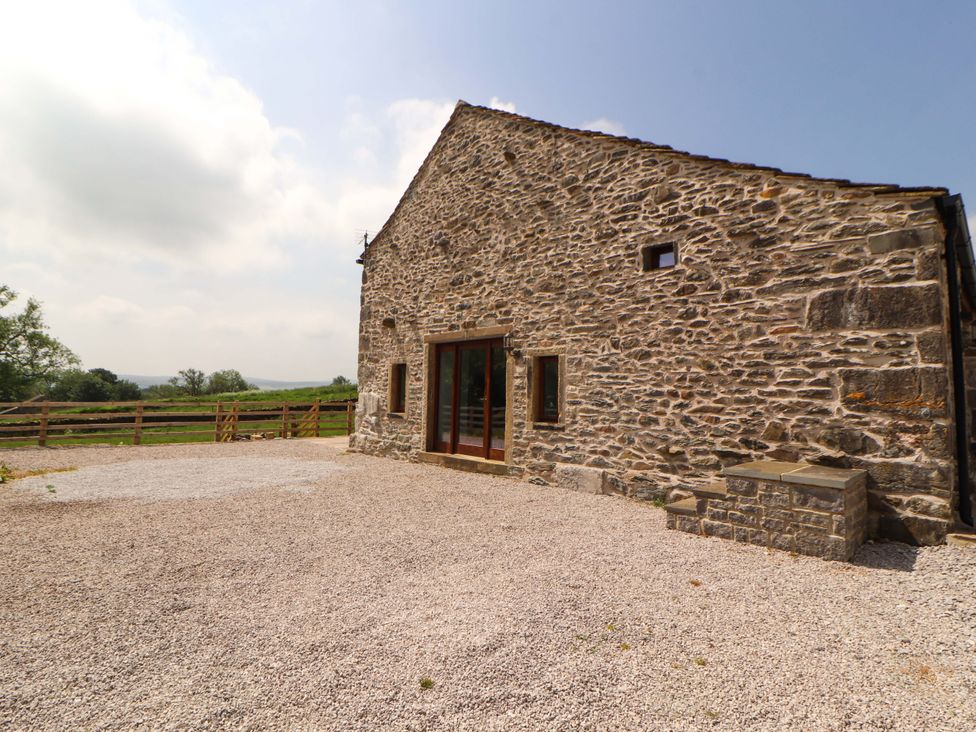 A stone house with a gravel area and fence at Dam House Barn Lancaster
