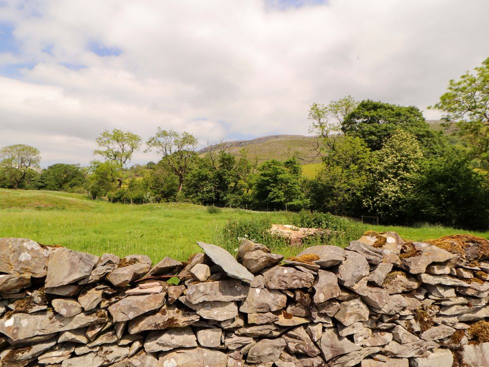 A view of a stone wall with trees and mountains at Dam House Barn in Lancaster