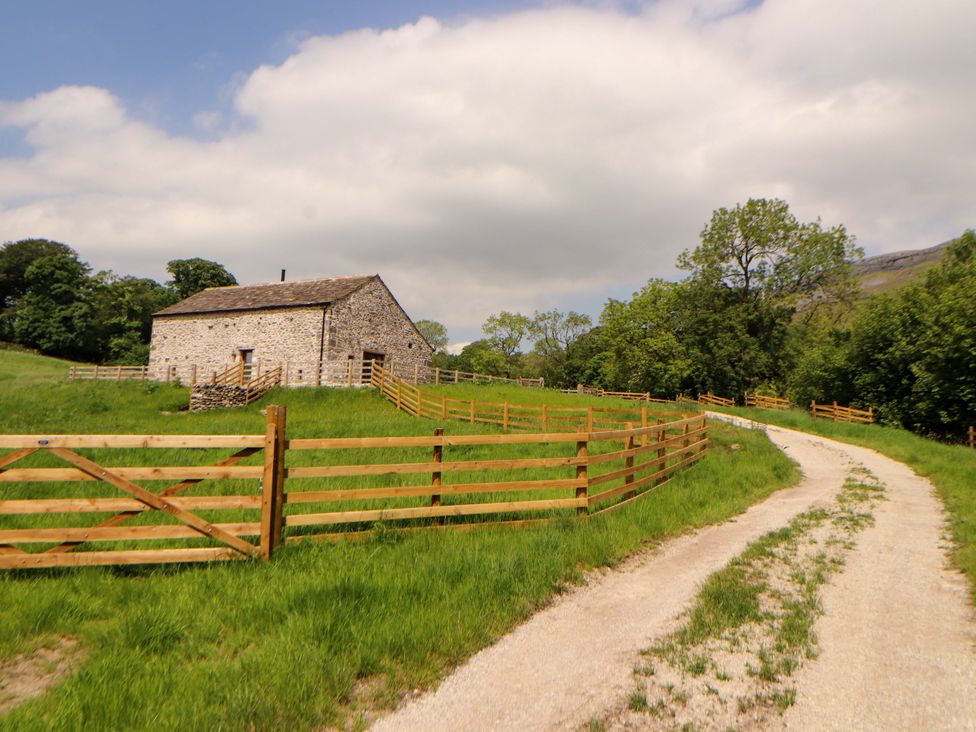 A barn surrounded by a wooden fence and grassy area at Dam House Barn, Lancaster
