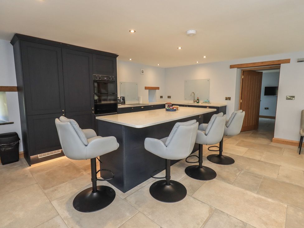 A kitchen with an island and bar stools at Dam House Barn in Austwick