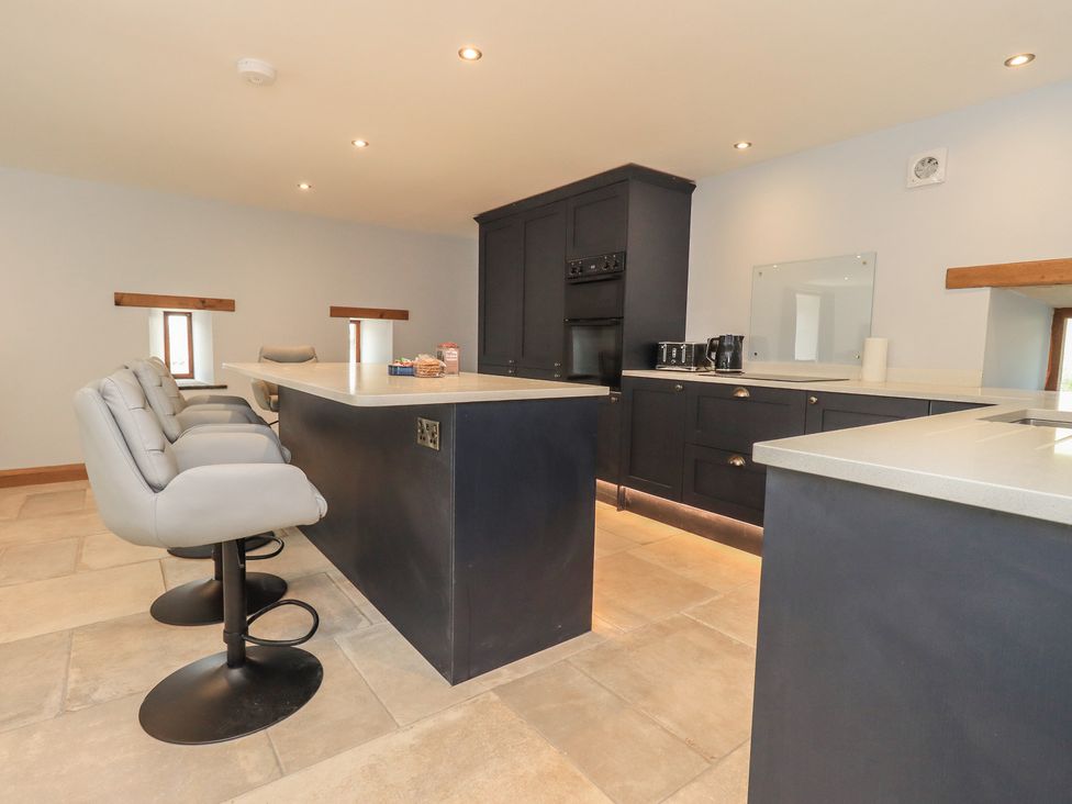 A kitchen with a kitchen island and bar stools at Dam House Barn in Austwick