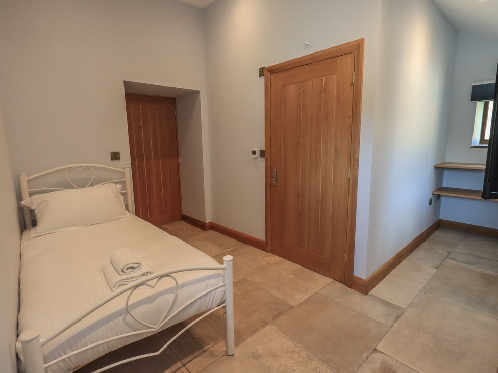 A bedroom with a single bed and a wooden door at Dam House Barn Austwick
