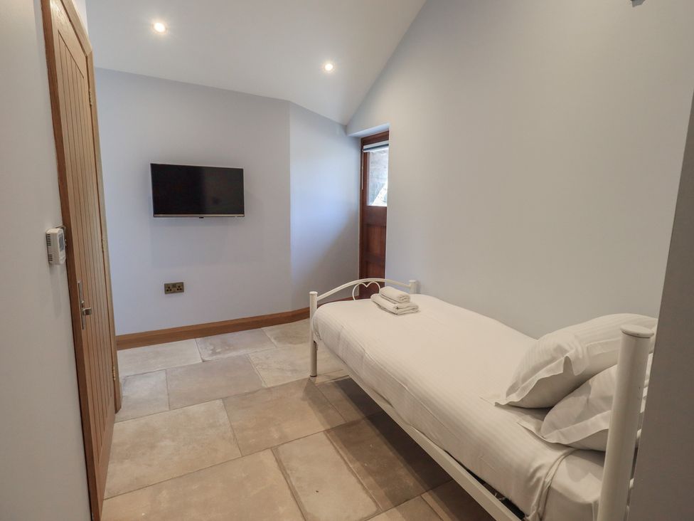 A bedroom with a bed and television at Dam House Barn Austwick