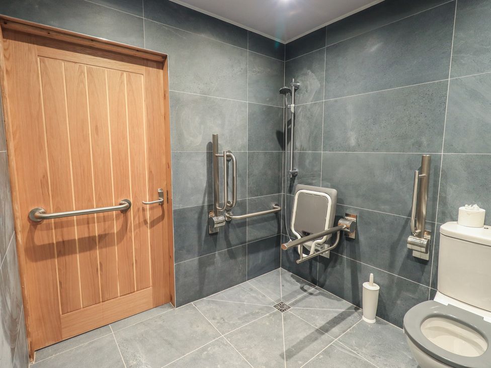 A bathroom with a shower, toilet, and grab bars at Dam House Barn, Austwick