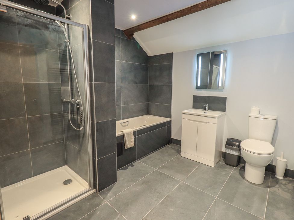 A bathroom with a shower, bathtub, sink, and toilet at Dam House Barn, Austwick