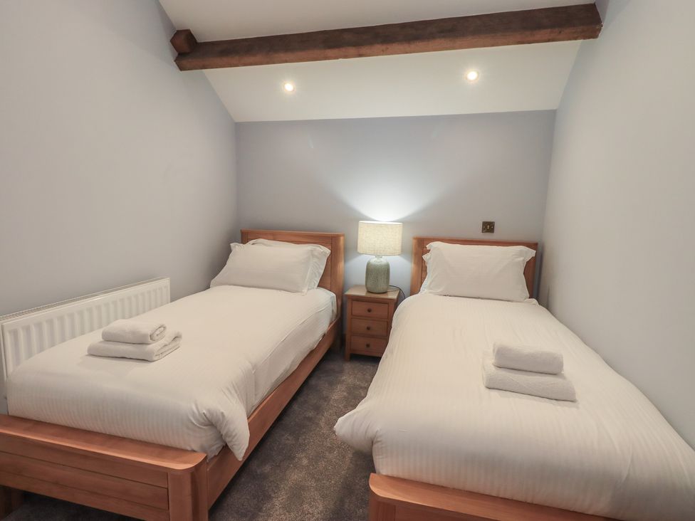 A bedroom with two single beds and a lamp at Dam House Barn Austwick