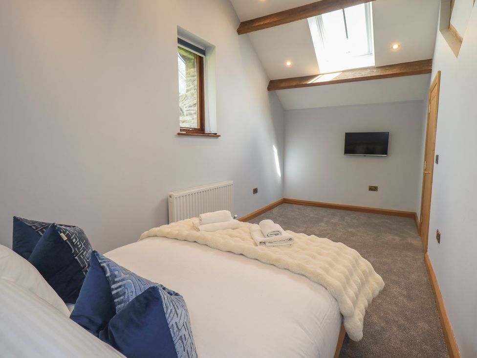 A bedroom with a bed and television at Dam House Barn in Austwick