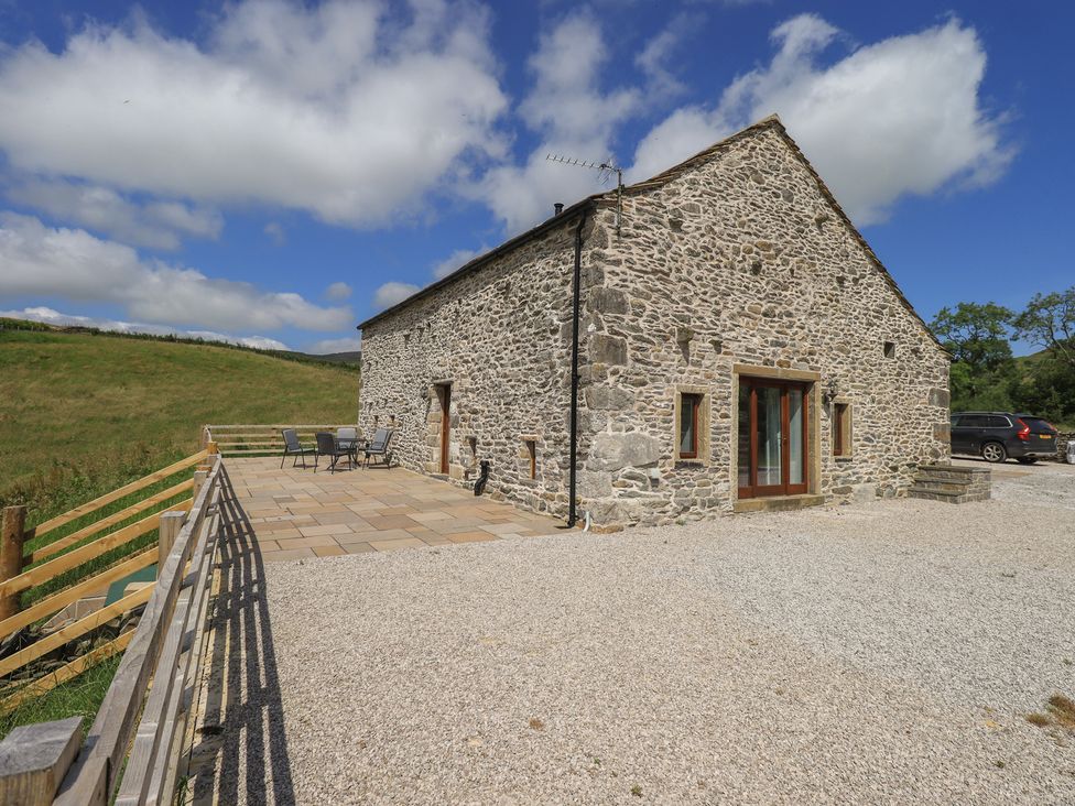 An outdoor view of a stone barn with seating area at Dam House Barn in Austwick