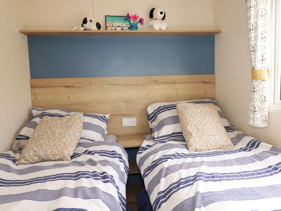 A bedroom with twin beds and a shelf with decorative items at 5 Silverbow 