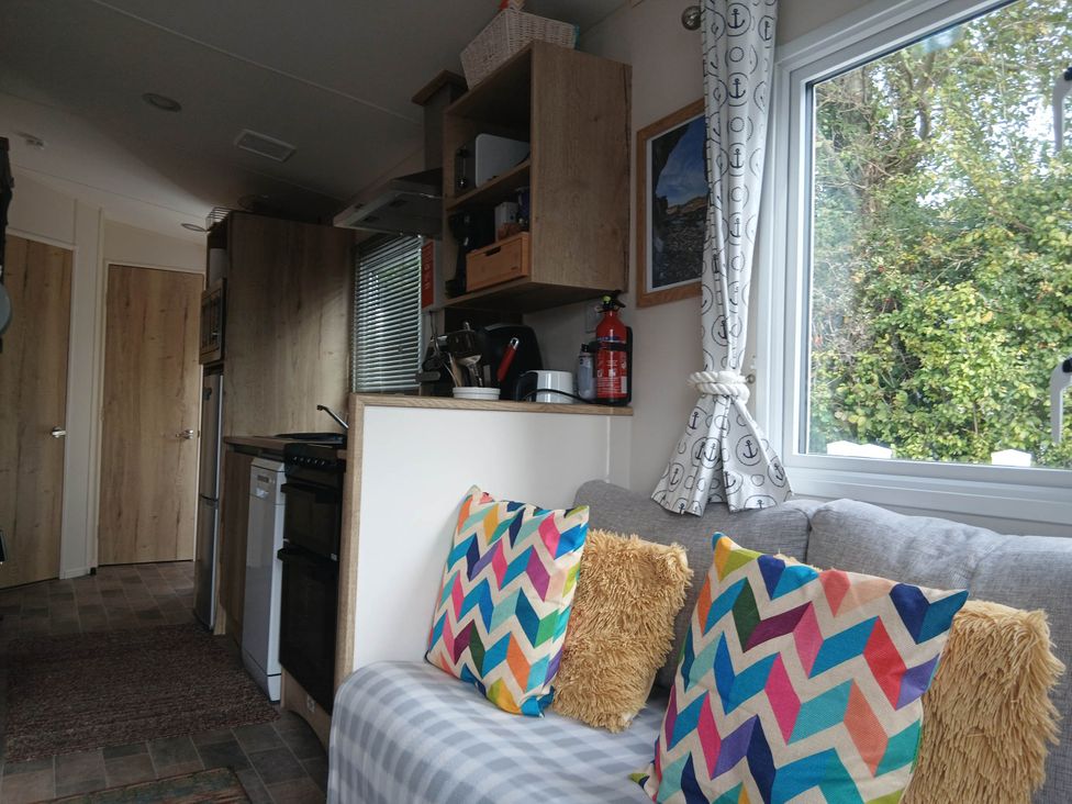A living room with a couch and kitchen appliances at Porthcurno 5 Perranwell near Goonhavern