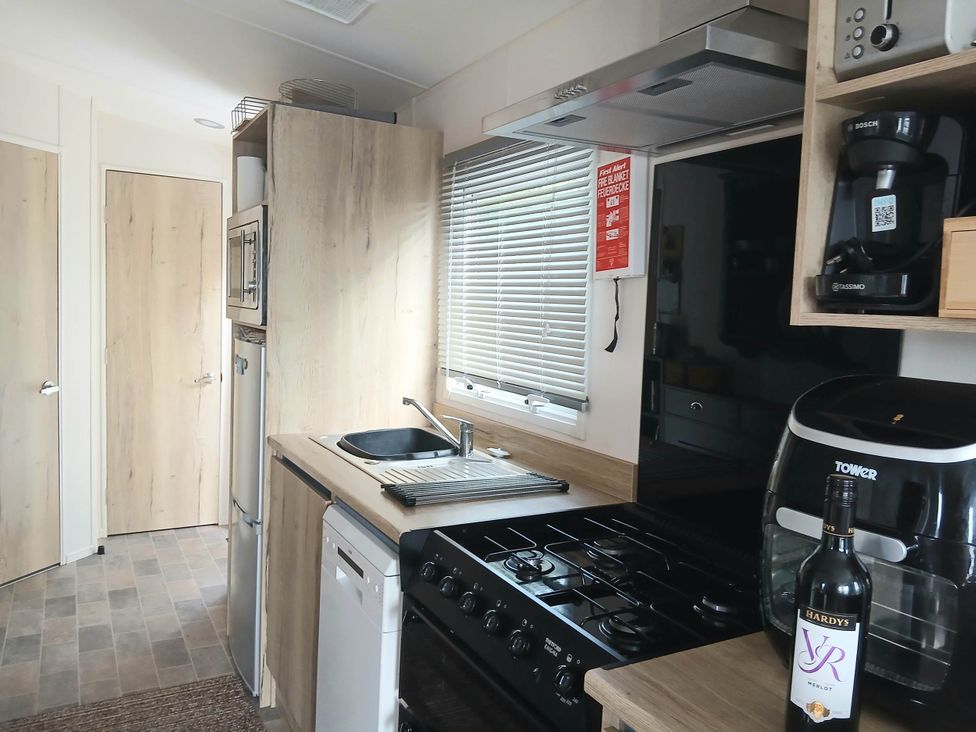 A kitchen with a sink, stove, and refrigerator at Porthcurno 5 Perranwell near Goonhavern