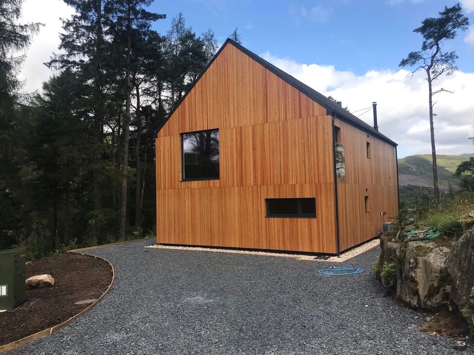 A house with wooden exterior and windows at Red Stag with stunning loch and waterfall view in Crianlarich