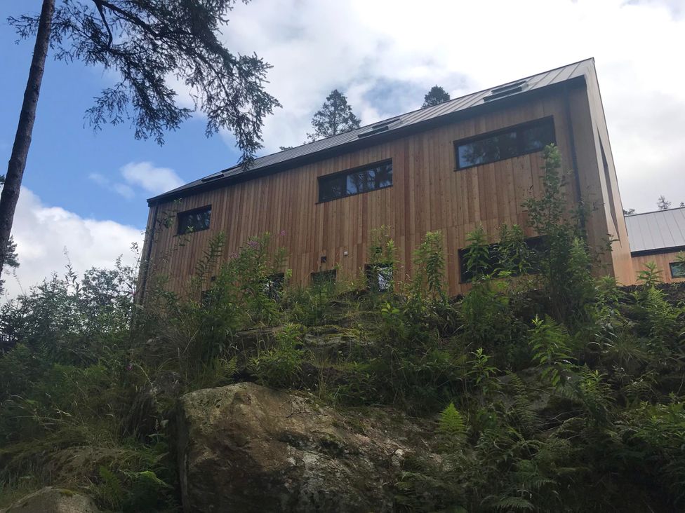 A building with wooden exterior surrounded by trees at Red Stag with stunning loch and waterfall view Crianlarich