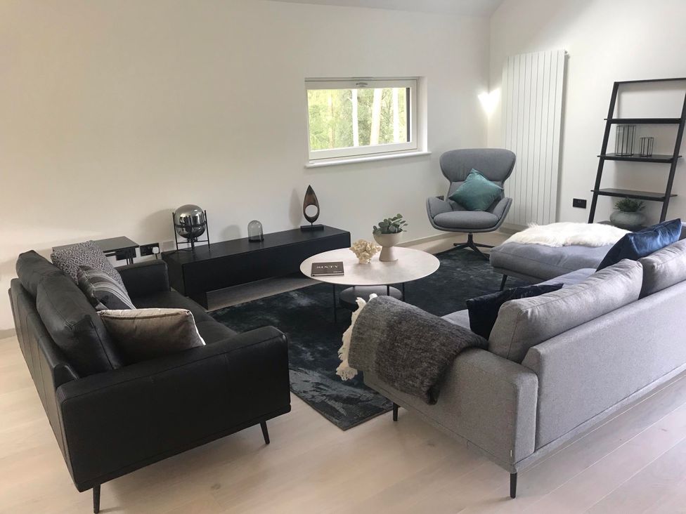 A living room with a sofa, coffee table, and armchair at Red Stag with stunning loch and waterfall view, Crianlarich