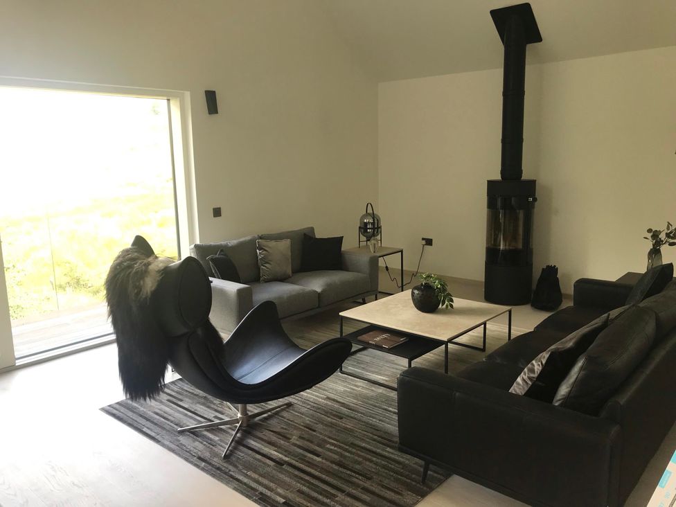 A living room with sofa and armchair at Red Stag with stunning loch and waterfall view, Crianlarich