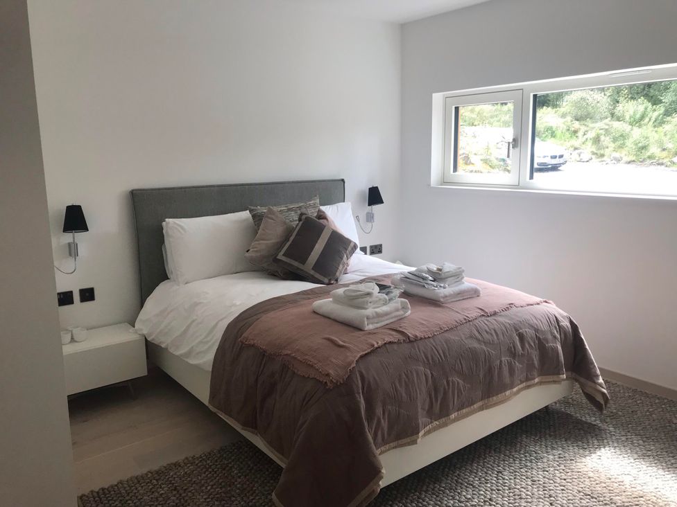 A bedroom with a bed and bedside table at Red Stag with stunning loch and waterfall view, Crianlarich