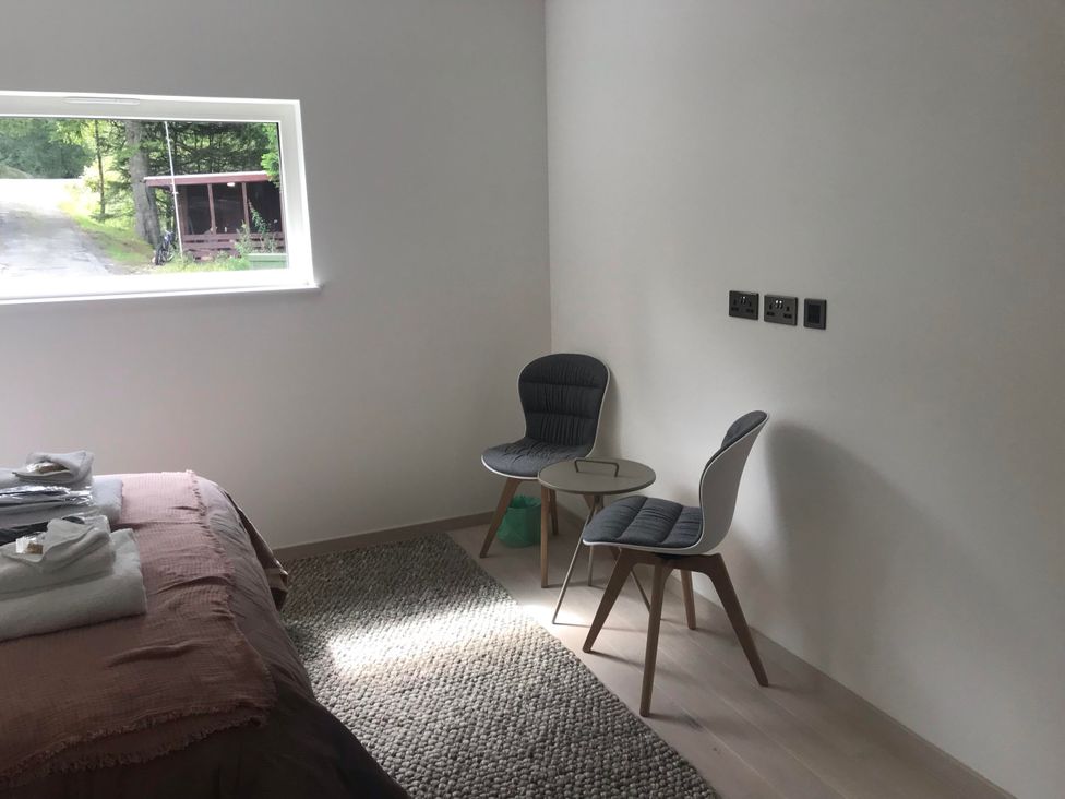 A bedroom with a bed and two chairs at Red Stag with stunning loch and waterfall view Crianlarich