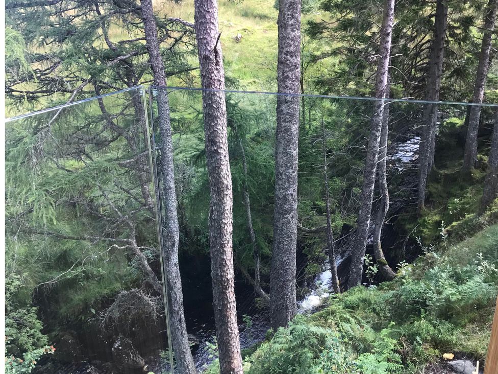 A view of a stream surrounded by trees at Red Stag with stunning loch and waterfall view in Crianlarich