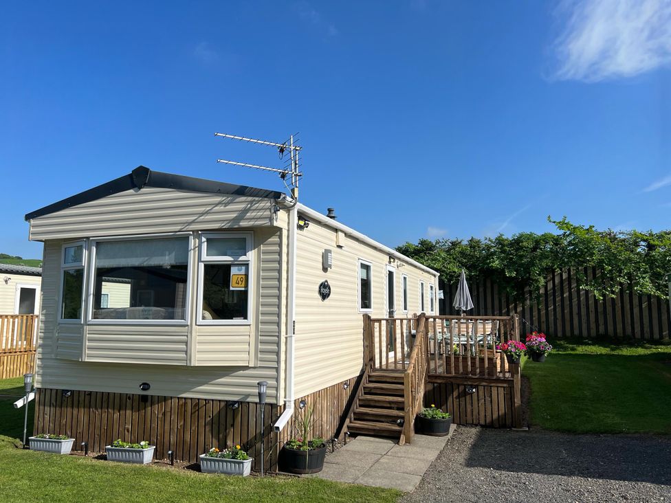 A caravan with a wooden deck and garden area at Hornshole Hideaway Caravan Hawick Riverside Caravan Park near Hawick