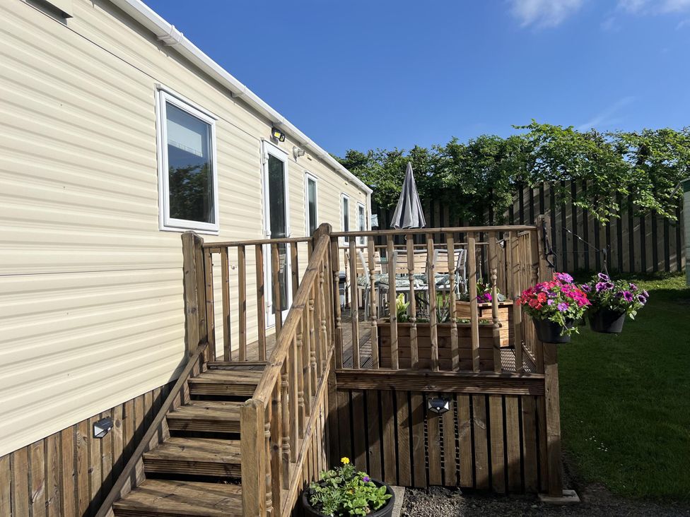 A caravan with a wooden deck and outdoor seating area at Hornshole Hideaway Caravan Hawick Riverside Caravan Park near Hawick