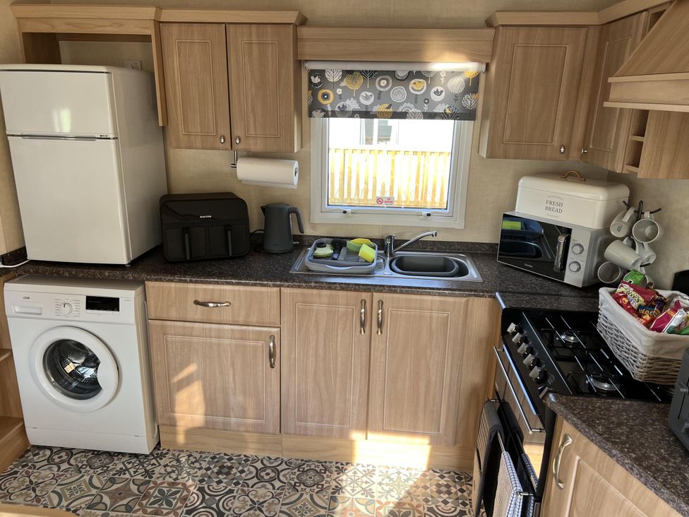 A kitchen with appliances and a window at Hornshole Hideaway Caravan Hawick near Riverside Caravan Park