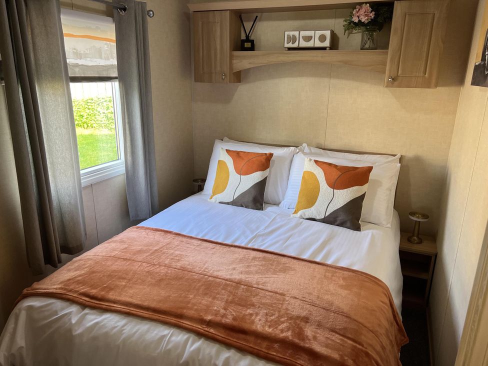 A bedroom with a double bed and decorative pillows at Hornshole Hideaway Caravan Hawick Riverside Caravan Park near Hawick