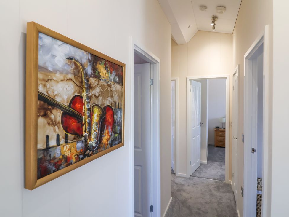 A hallway with artwork on the wall and doors leading to other rooms at Banksy, Mullacott Park near Ilfracombe