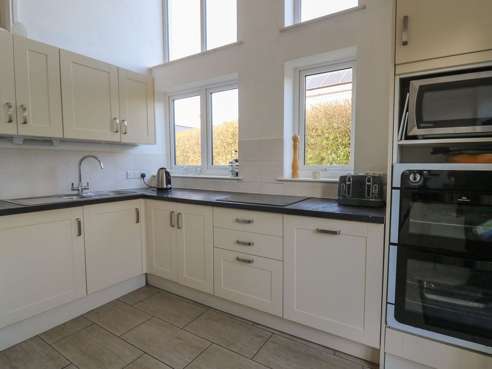 A kitchen with cabinets, sink, kettle, and toaster at Tegfan in Newport