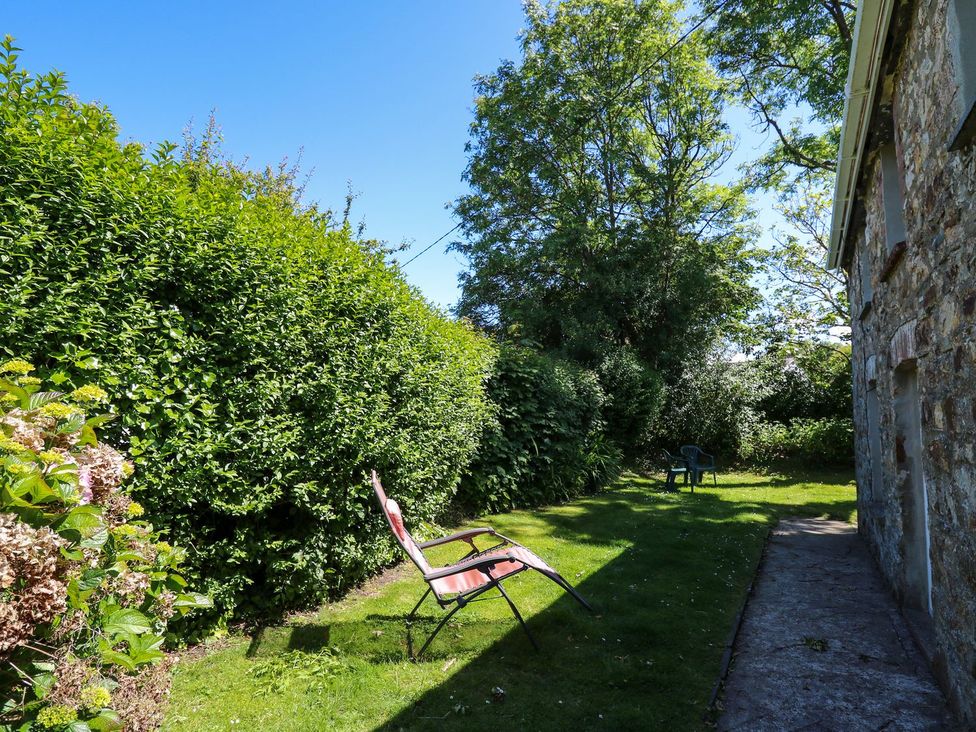 A garden with lawn, hedges, and chairs at Tegfan in Newport