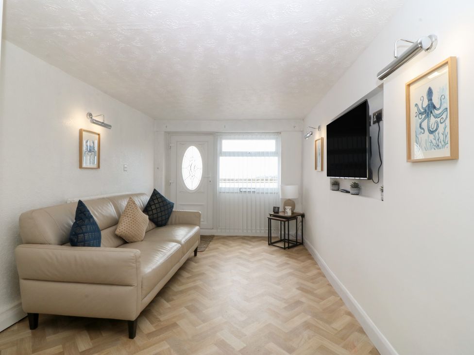 A living room with a sofa and TV at Porth Ewyn House in Trearddur Bay
