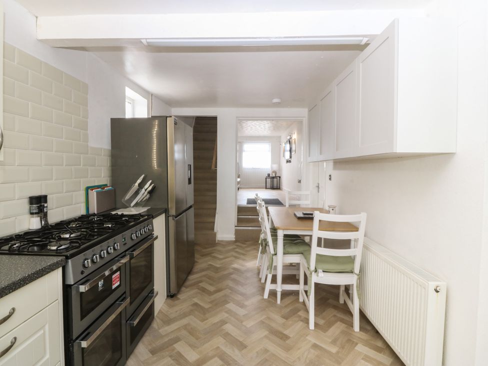 A kitchen with an oven, refrigerator, and dining table at Porth Ewyn House in Trearddur Bay