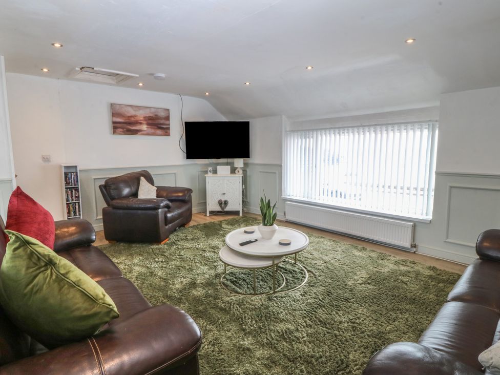A living room with a television and sofa at Porth Ewyn House in Trearddur Bay