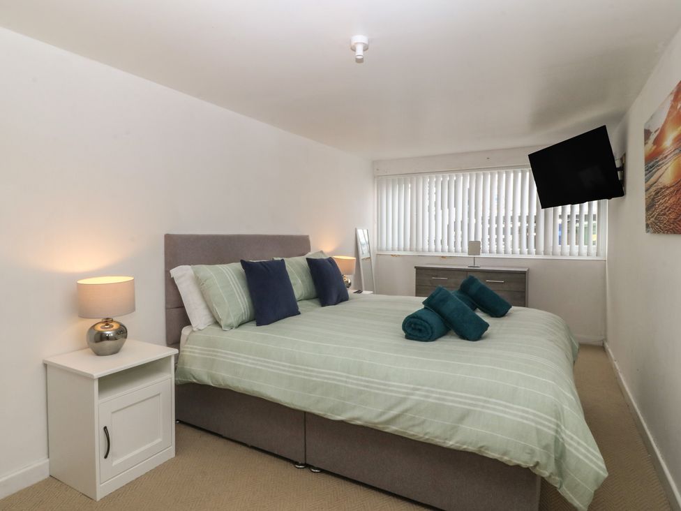 A bedroom with a bed, bedside table and television at Porth Ewyn House, Trearddur Bay